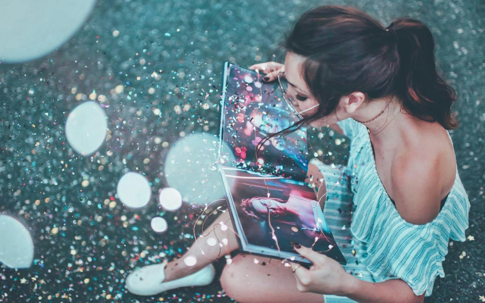 Kvinne som blåser glitterstøv fra et bilde i en bok
