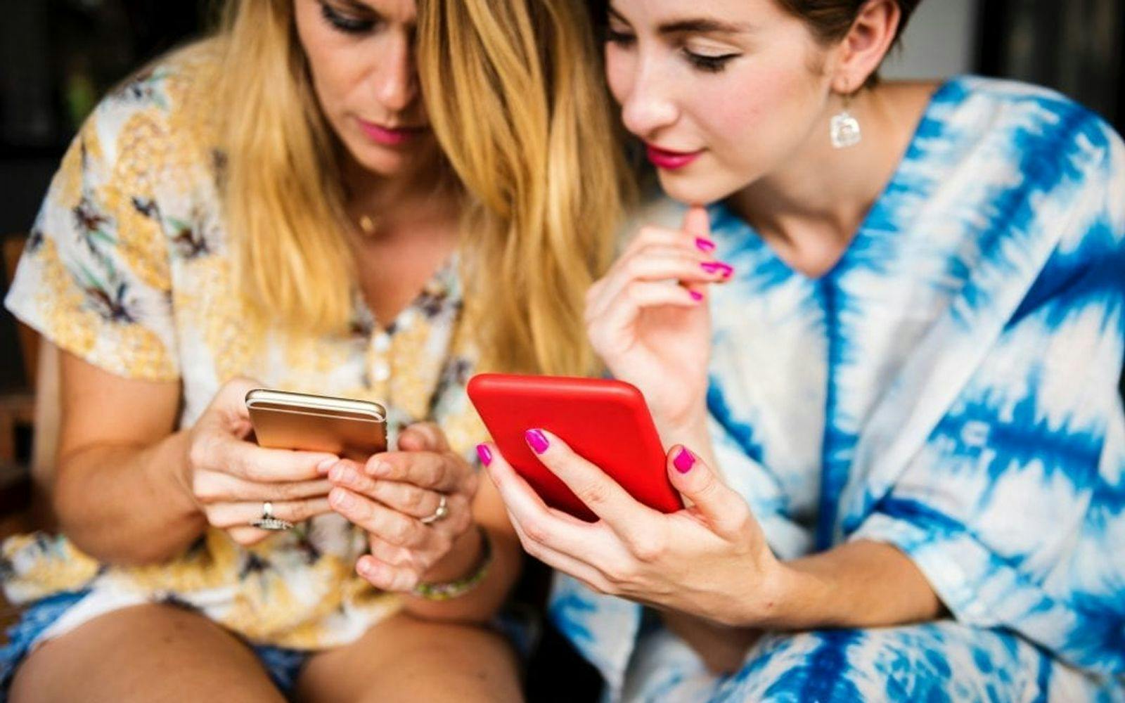 To kvinner som ser på smartelefonene sine sammen