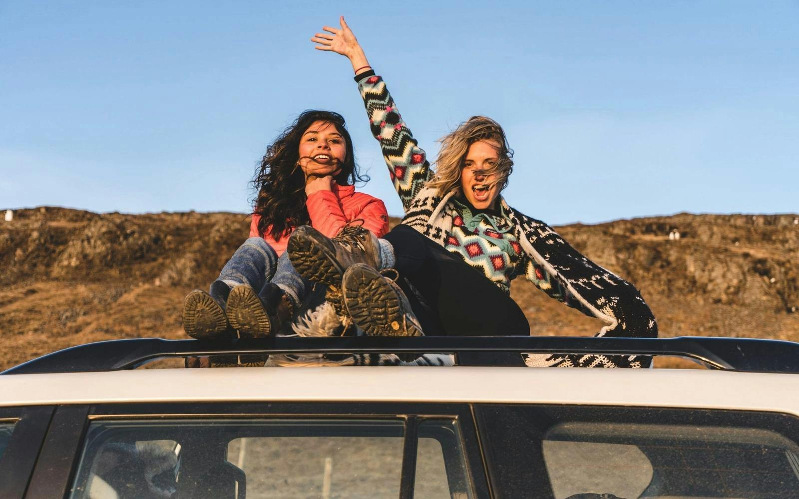 To kvinner som vinker på toppen av et biltak
