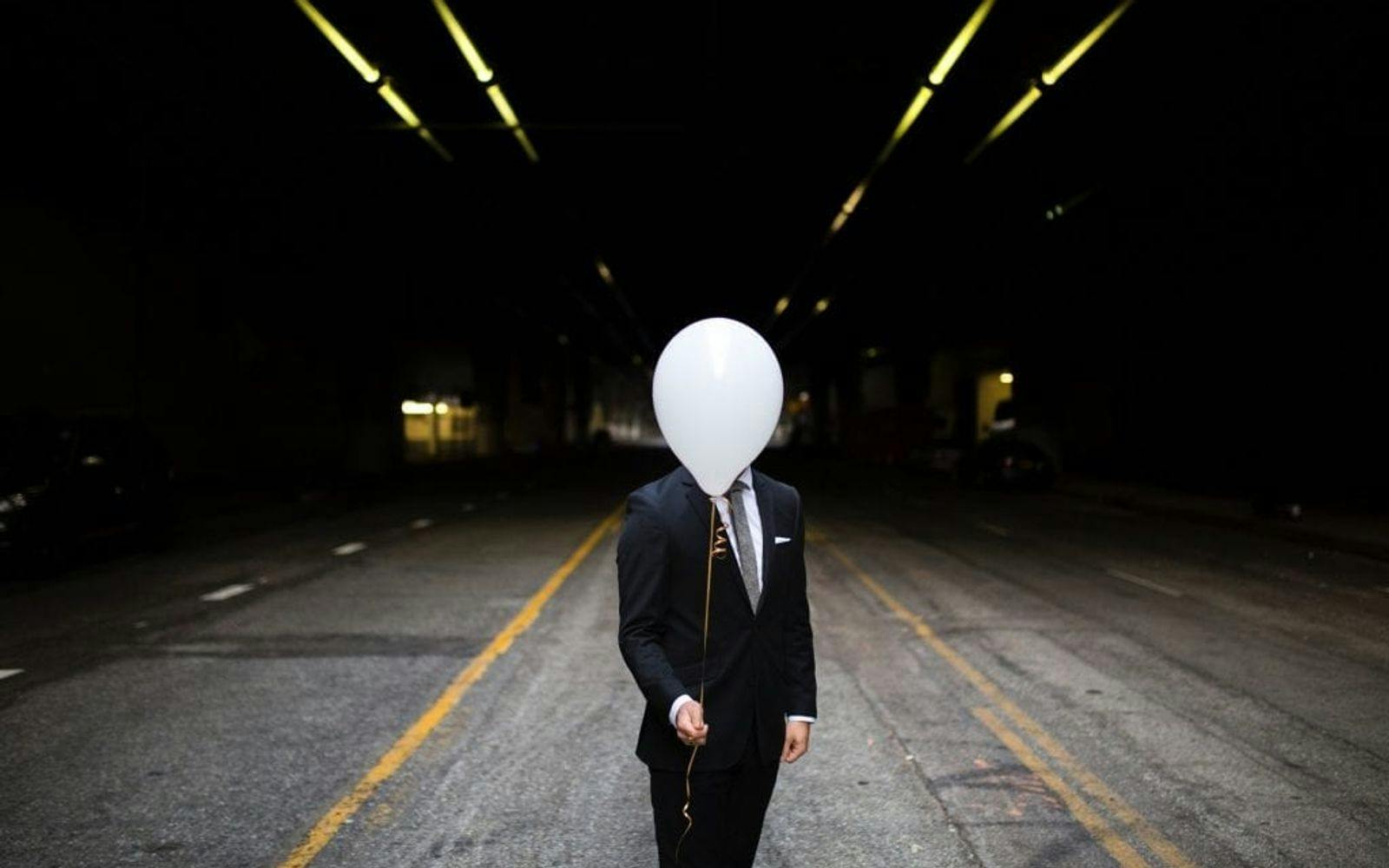 Mann som er anonymisert ved å holde en ballong foran ansiktet