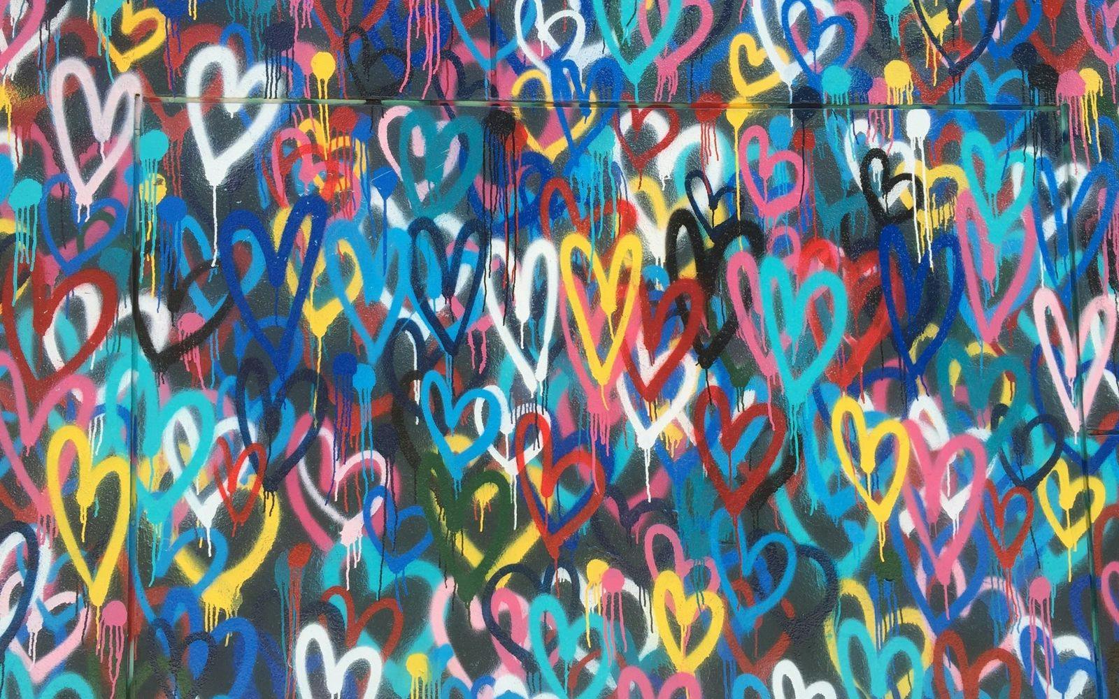 Vegg med grafitti fullt av fargerike hjerter