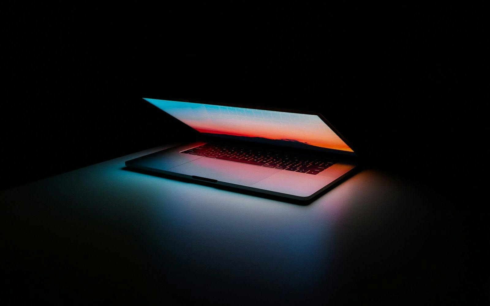 En halvåpen laptop som lyser rosa