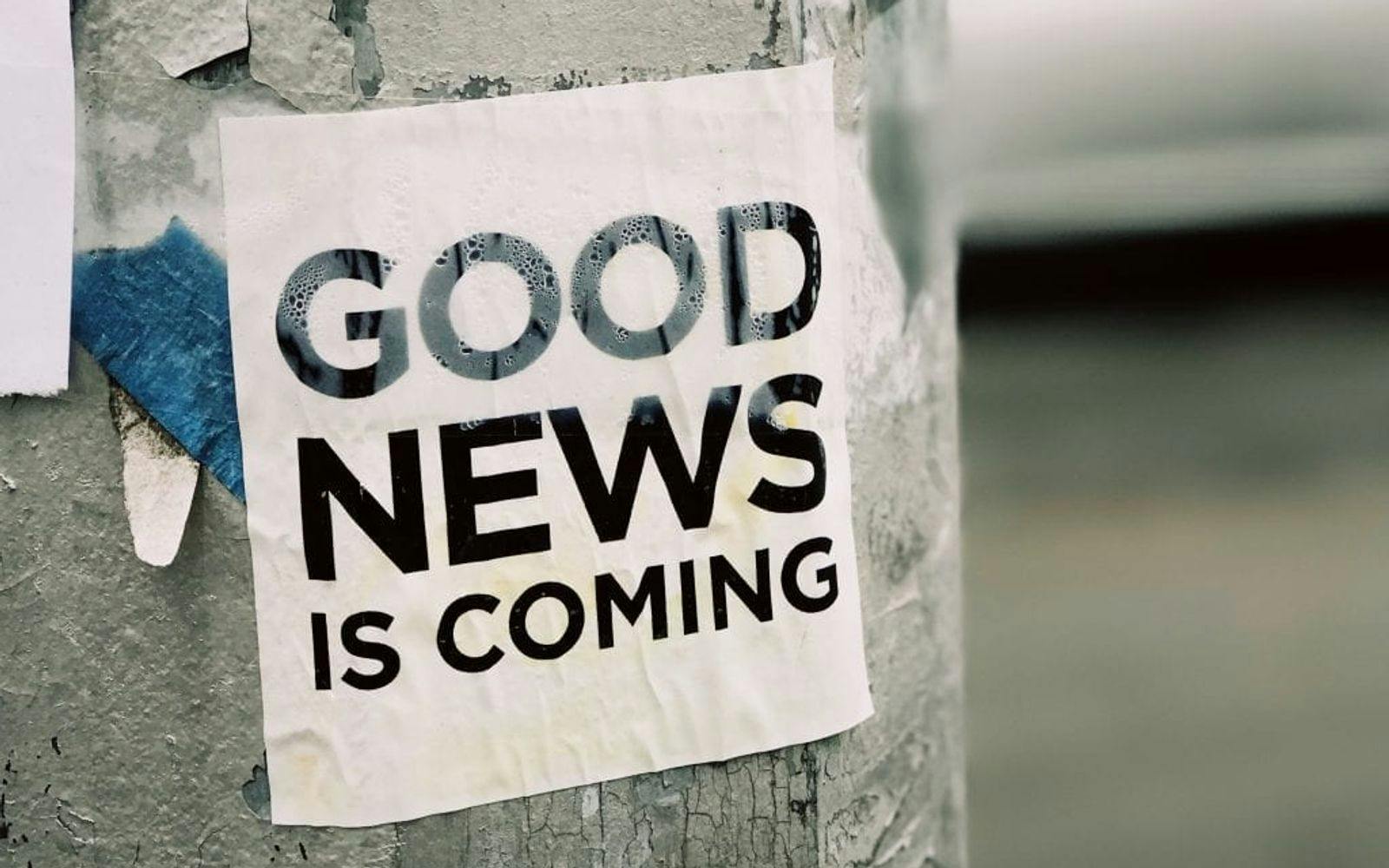 Klistremerke med teksten "Good news is coming" på en nedslitt lyktestolpe